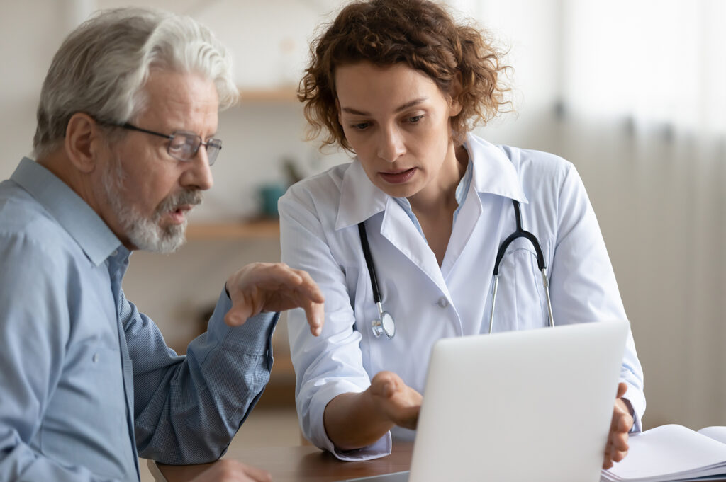 young 30s female  physician showing test results on computer to focused middle aged older patient 